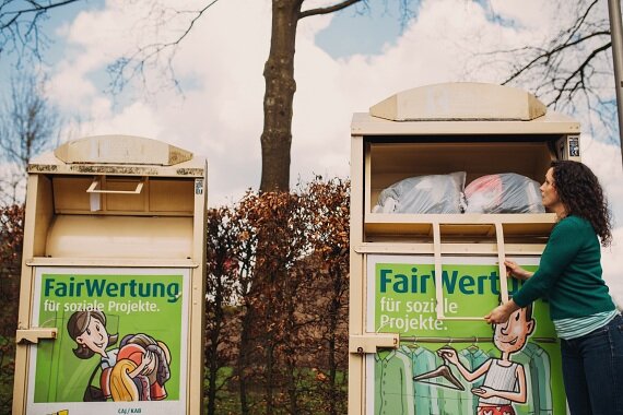Frau wirft Kleidersäcke in FairWertung-Container