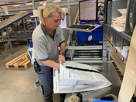 Mitarbeiterin verpackt Sendung im Logistiklager
