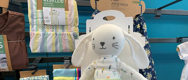 Stoffhase vor Kinderkleidung im Laden