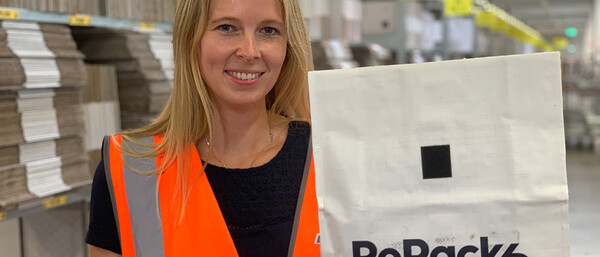 Person im Lager mit Warnweste hält RePack-Tasche