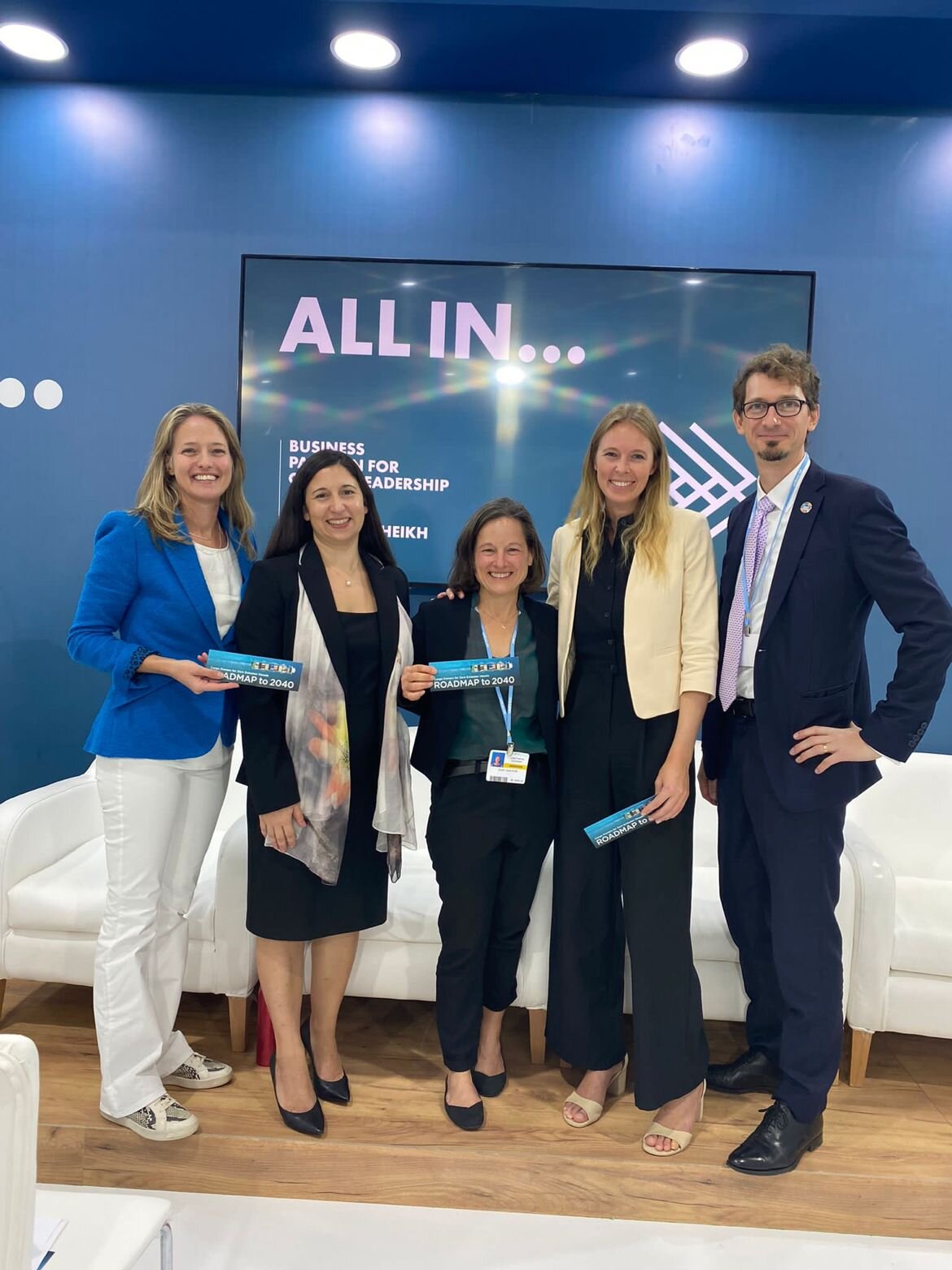 Fünf Geschäftsleute vor „ALL IN“-Konferenzwand