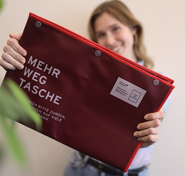 Person hält rote Mehrwegtasche vor sich