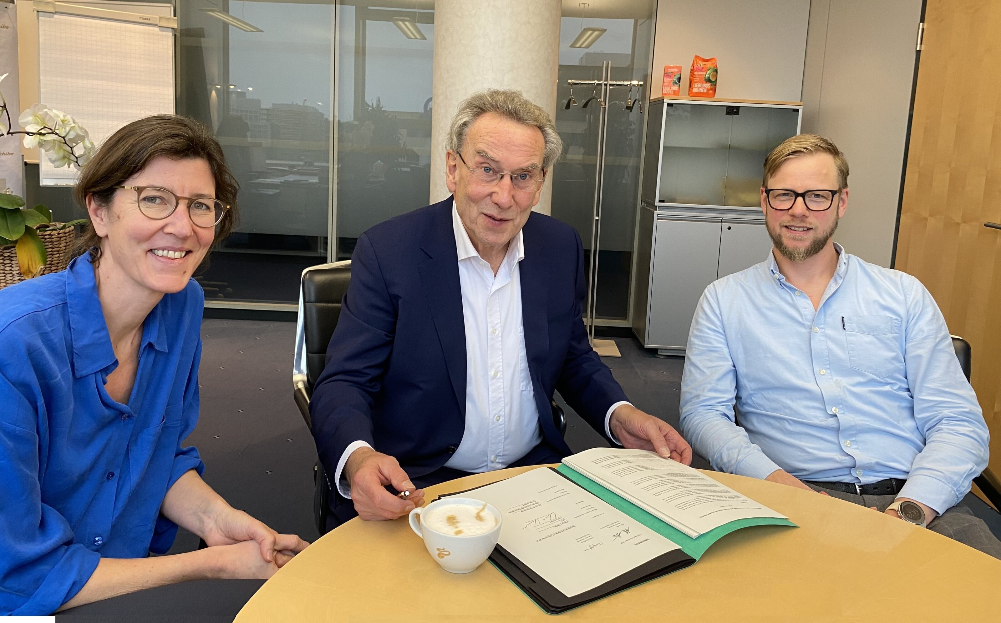 Drei Personen bei Vertragsbesprechung am Konferenztisch