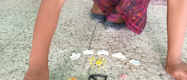 Kind kniet am Boden und spielt mit Knetfiguren