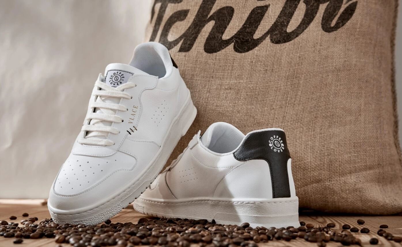 Weiße Sneaker auf Kaffeebohnen vor Jutesack