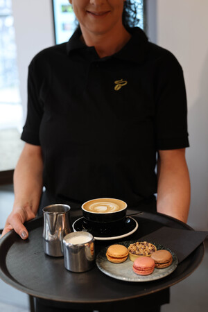 Link: Großansicht des Bildes - Bildinhalt: Kellnerin mit Cappuccino, Milch und Macarons