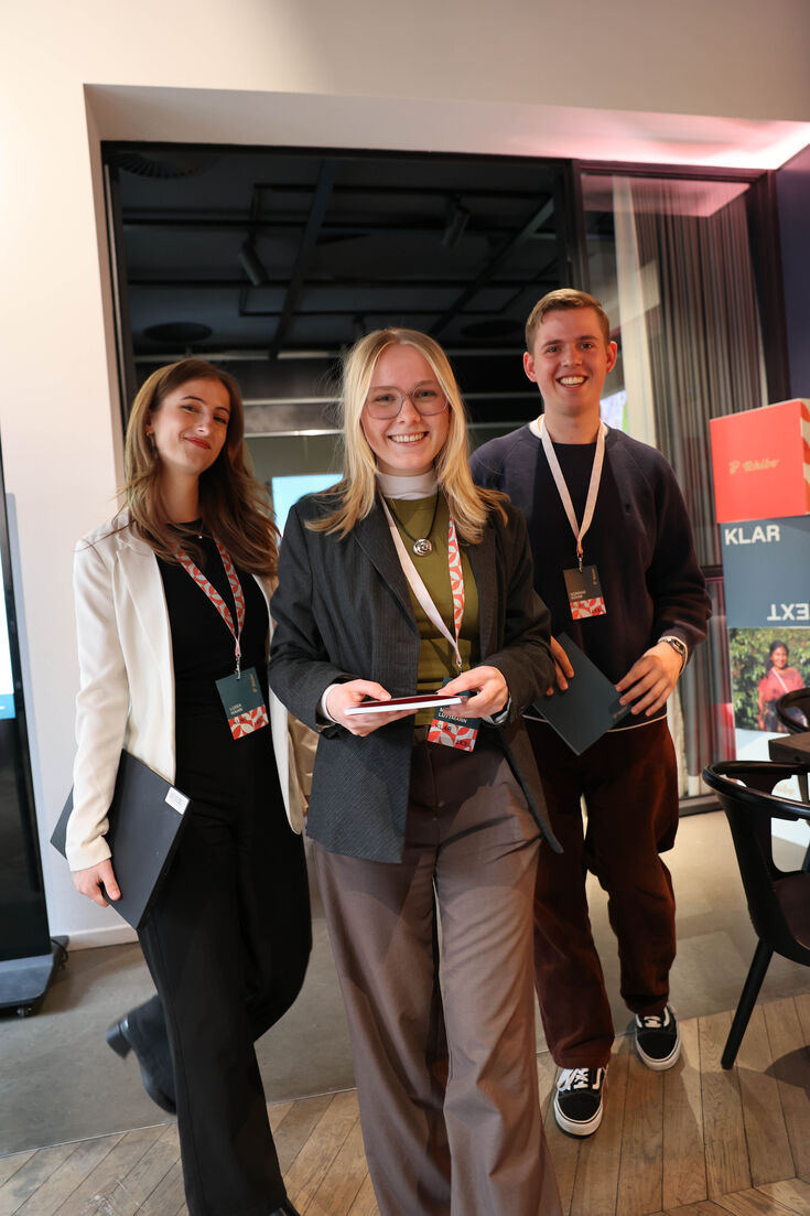 Drei Personen mit Konferenzbadges im Büro