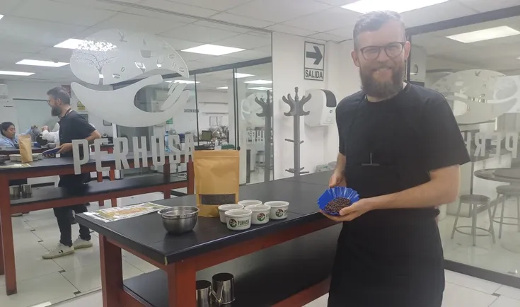 Barista mit Kaffeebohnen in Tasse auf Probiertisch