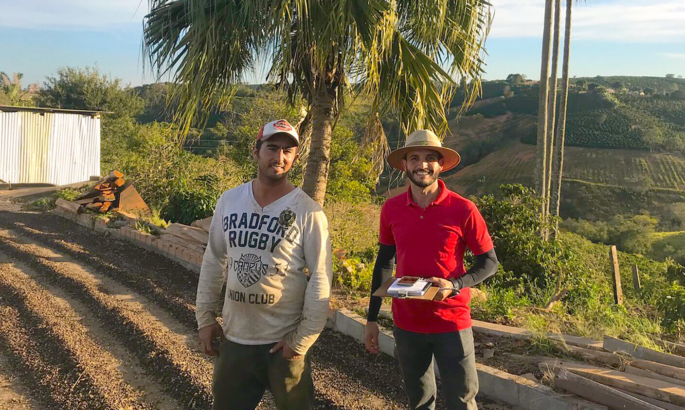 Ein Kaffeefarmer mit einem Mitarbeiter von Enveritas auf einer Kaffeefarm