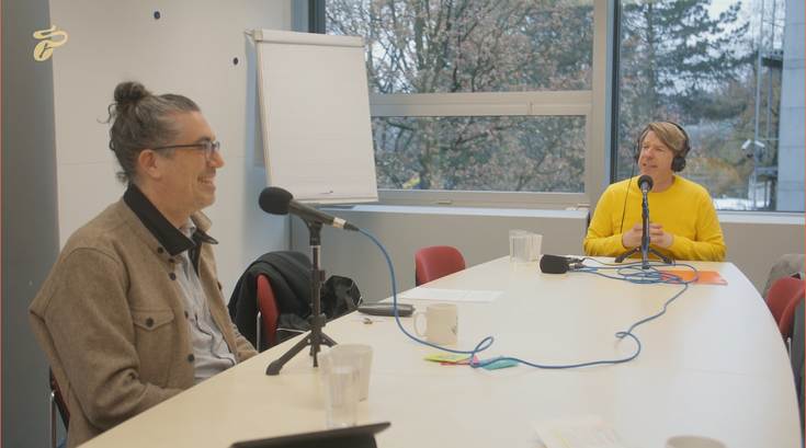 Two people recording a podcast at a table