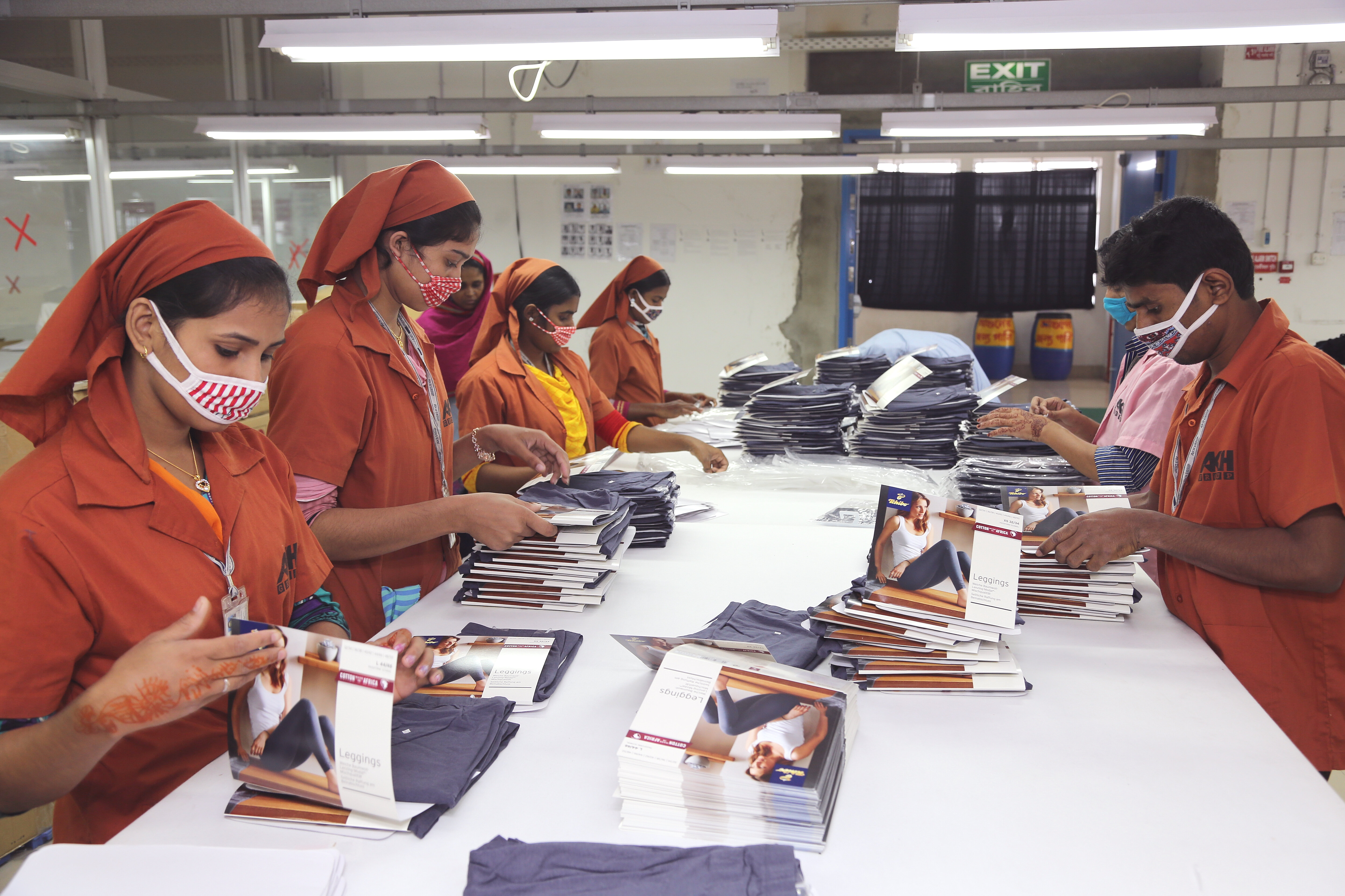 Factory workers folding and packaging leggings